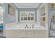 Close up of a soaking tub featuring white tile and cabinetry, with natural light coming through a shuttered window at 603 Lakewood Dr, Social Circle, GA 30025