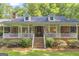 Inviting covered front porch with brick accents, decorative flag, and Welcome sign at the entrance at 603 Lakewood Dr, Social Circle, GA 30025