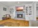 Cozy living room highlighting a brick fireplace with a TV, shelving, and hardwood floors at 603 Lakewood Dr, Social Circle, GA 30025