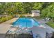 Sparkling blue pool surrounded by a patio, with comfortable lounge furniture and lush greenery for privacy at 603 Lakewood Dr, Social Circle, GA 30025