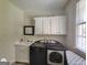 A compact laundry room features modern washer and dryer, sink, and upper storage cabinets at 1292 Hidden Spirit Trl, Lawrenceville, GA 30045