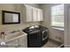 Functional laundry room with a sink, modern washer/dryer, and storage cabinets at 1292 Hidden Spirit Trl, Lawrenceville, GA 30045
