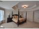 A spacious main bedroom boasts a four-poster bed, tray ceiling, bedside tables and generous closet space at 1292 Hidden Spirit Trl, Lawrenceville, GA 30045