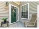 A charming front porch featuring neutral siding, a green door and a quaint sitting area at 512 Las Brasis Ct, Peachtree City, GA 30269