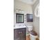 A stylish half bathroom features a dark vanity, modern mirror, toilet and unique circular window at 70 N Strathmore Dr, Sharpsburg, GA 30277