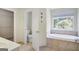 Bathroom featuring soaking tub next to window and access to walk-in closet at 70 N Strathmore Dr, Sharpsburg, GA 30277