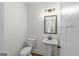 Bright bathroom with white toilet, pedestal sink, vanity lighting, and black framed mirror at 4585 Parkwood Rd, Social Circle, GA 30025
