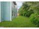 Side view of fenced backyard with manicured green lawn, lush trees, and blue siding at 4753 Klondike Cv, Lithonia, GA 30038