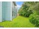 Side view of fenced backyard with manicured green lawn, lush trees, and blue siding at 4753 Klondike Cv, Lithonia, GA 30038