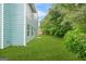 Side view of fenced backyard with manicured green lawn, lush trees, and blue siding at 4753 Klondike Cv, Lithonia, GA 30038