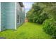 Side view of fenced backyard with manicured green lawn, lush trees, and blue siding at 4753 Klondike Cv, Lithonia, GA 30038