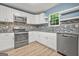 Well-lit kitchen boasts white cabinets, modern appliances, granite counters, tile backsplash, and wood-look flooring at 4753 Klondike Cv, Lithonia, GA 30038