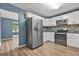 Modern kitchen showcasing stainless steel appliances, white cabinets, a mosaic tile backsplash, and wood-look flooring at 4753 Klondike Cv, Lithonia, GA 30038