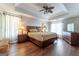Spacious primary bedroom featuring hardwood floors, a tray ceiling, and soft, natural lighting at 130 Bexar Ct, Johns Creek, GA 30022