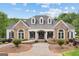 Charming stone and white home with arched windows, dormers, and manicured landscaping at 495 Stonehaven Dr, Fayetteville, GA 30215