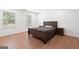 Well-lit bedroom with hardwood floors, a large bed and two windows allowing for natural light at 9477 Forest Knoll Dr, Jonesboro, GA 30238