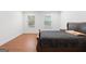 Clean bedroom with hardwood floors, a large bed and two windows allowing for natural light at 9477 Forest Knoll Dr, Jonesboro, GA 30238