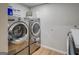 Laundry room with modern stainless-steel washer and dryer and white storage at 403 Chester Piper Rd, Covington, GA 30014