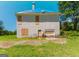 Rear view of the two-story house shows a boarded-up garage and windows with a blue tarp on the roof at 145 Windy Ridge Ct, Fayetteville, GA 30214
