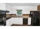 Functional kitchen featuring white cabinets, black appliances, brick backsplash, and a window at 1517 Indian Forest Trl, Stone Mountain, GA 30083