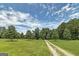 View of the property with long driveway leading to house and surrounded by lush greenery and blue skies at 949 Amelia Rd, Locust Grove, GA 30248