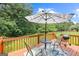 Back deck with a table, umbrella, grill, and fenced in yard with a lush green tree line at 20 Knollwood Pl, Covington, GA 30014