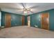 Spacious bedroom showcasing neutral carpet, ceiling fan, three doors, and a glimpse into an en-suite bathroom at 390 Stoneridge Way, Fayetteville, GA 30215