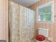 Bathroom showcasing a toilet, shower with curtain, and a window offering natural light at 829 Bev Ct, Lawrenceville, GA 30046