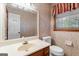 Cozy bathroom with wallpaper, a single vanity, and framed mirror at 829 Bev Ct, Lawrenceville, GA 30046
