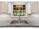 Well-lit kitchen sink with granite countertop and a window overlooking a lush backyard at 829 Bev Ct, Lawrenceville, GA 30046