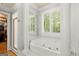 Bright bathroom featuring a tub with columns, shower, and plantation shutters for natural light at 9125 Patrick Pl, Winston, GA 30187