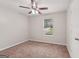 Neutral bedroom features a ceiling fan, carpeted floor, and bright natural light from the window at 7335 Connell Rd, Fairburn, GA 30213