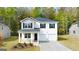 Traditional two-story home with a covered front porch and a two-car garage, set in a lush green lawn at 143 Oakchase Park Ln, Hampton, GA 30228