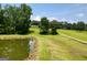 Aerial view of a property with a pond, green fields, and a long driveway at 10215 Creel Rd, Chattahoochee Hills, GA 30213