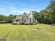 Beautiful home with stone details, green lawn, mature trees, and circular fire pit at 10215 Creel Rd, Chattahoochee Hills, GA 30213