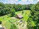 Aerial view of barn, garden and fenced yard surrounded by dense green forest at 250 Friendship Church Rd, Brooks, GA 30205