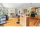 View of the kitchen with wood floors, featuring an island with bar stools, a fireplace, and modern appliances at 250 Friendship Church Rd, Brooks, GA 30205