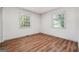 Bright bedroom featuring laminated wood flooring, base molding, and two windows at 234 Kenilworth Cir, Stone Mountain, GA 30083