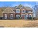 Charming two-story brick home with lush front lawn and manicured landscaping, under a bright blue sky at 6142 Golf View Xing, Locust Grove, GA 30248
