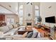 Bright living room boasts soaring ceilings, fireplace, abundant natural light, and plush, neutral furniture at 6142 Golf View Xing, Locust Grove, GA 30248