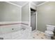 Bathroom featuring a white tub, a walk-in shower, and a toilet at 310 Trestle Rd, Locust Grove, GA 30248