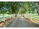 A long driveway lined with mature trees and a white fence, leading to the property at 310 Trestle Rd, Locust Grove, GA 30248