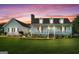 Inviting home exterior with a welcoming front porch, dormer windows, brick chimney and manicured lawn at sunset at 310 Trestle Rd, Locust Grove, GA 30248