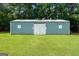 Large blue outbuilding with double doors and two windows, set against a green lawn at 310 Trestle Rd, Locust Grove, GA 30248