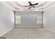A spacious primary bedroom featuring a tray ceiling and carpeted floor at 230 Hummingbird Ct, Hampton, GA 30228