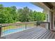 A wooden deck offers a view of the in-ground pool and verdant backyard at 230 Hummingbird Ct, Hampton, GA 30228