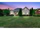 Dusk view of a brick home highlighting a lush lawn, manicured greenery, and architectural charm at 230 Hummingbird Ct, Hampton, GA 30228