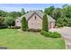 This brick home is surrounded by manicured landscaping, trees, and a well-kept lawn at 230 Hummingbird Ct, Hampton, GA 30228