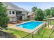 Backyard view of a sparkling in-ground pool, spacious deck, and a well-manicured lawn at 230 Hummingbird Ct, Hampton, GA 30228