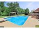 Backyard pool with a gazebo, swing set, dive board, and patio furniture on a sunny day at 230 Hummingbird Ct, Hampton, GA 30228